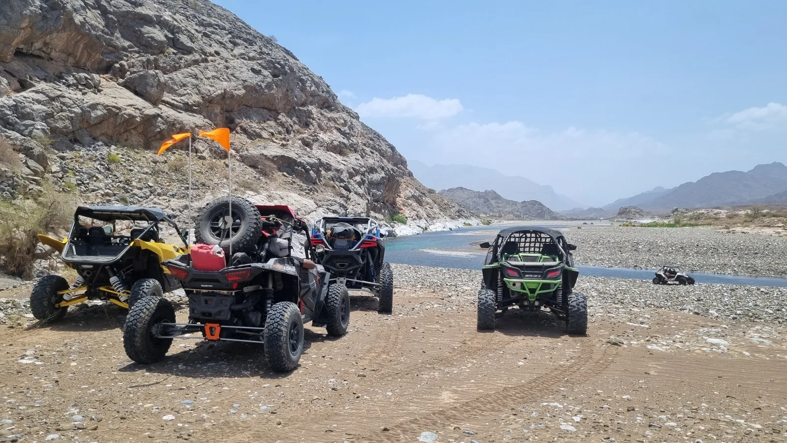 FOX ATVs vehicles stopped near water and rocky cliffs during an earlier wadi journey