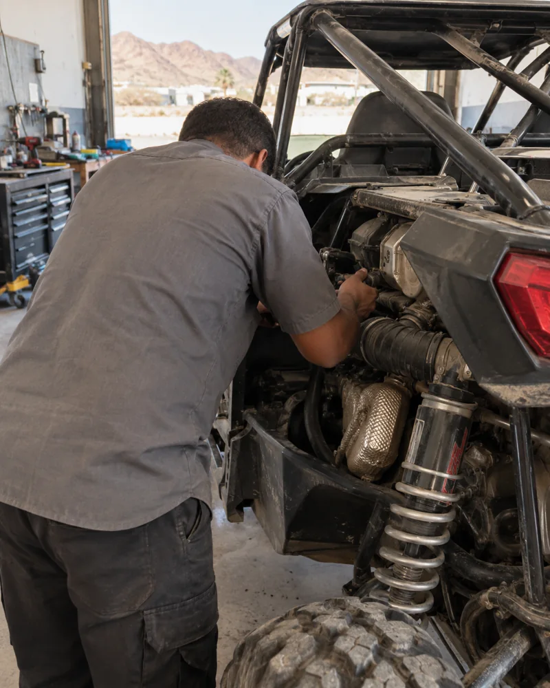 Illustrative workshop scene of a technician inspecting a buggy with his face turned toward the engine