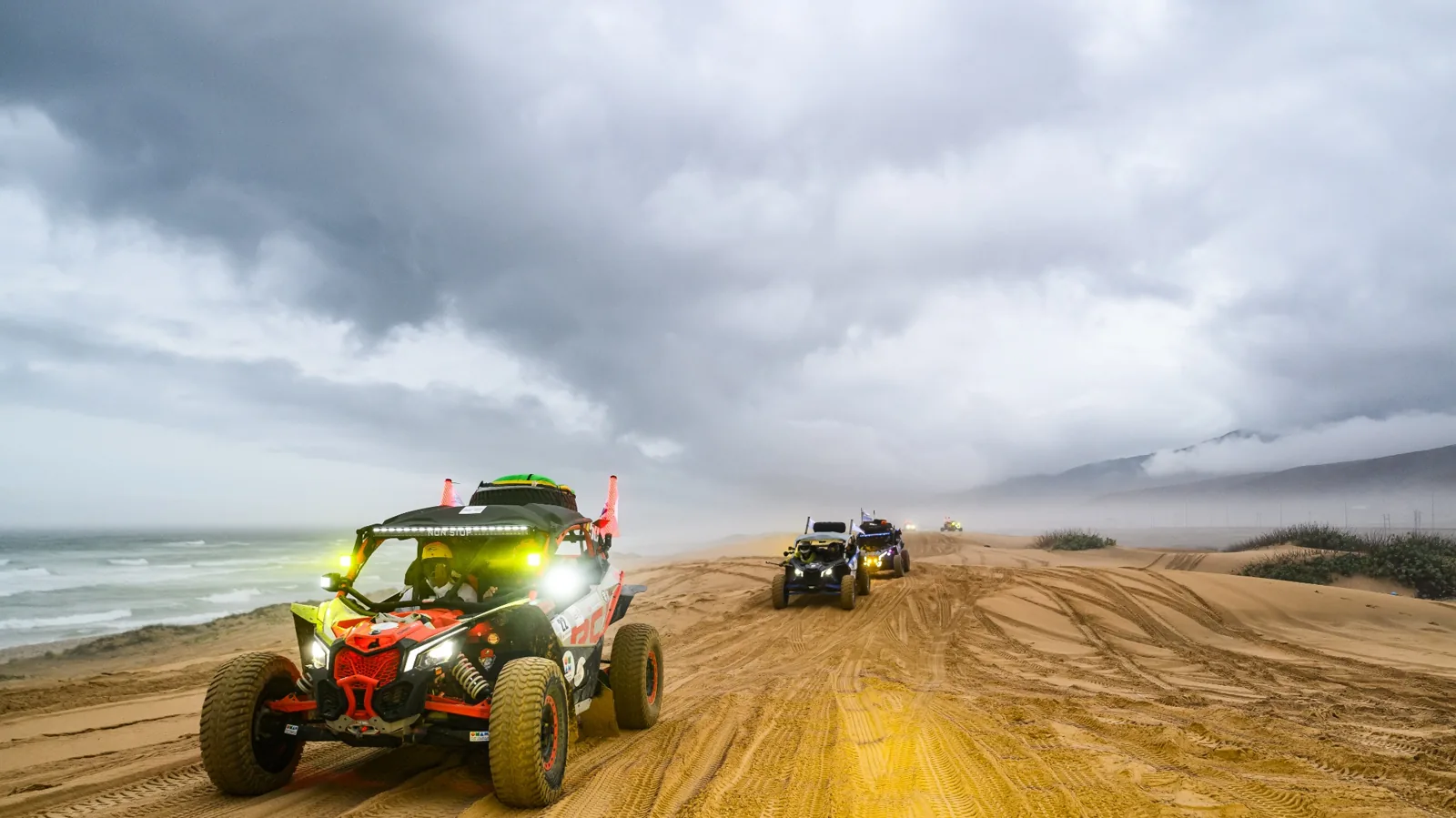 FOX ATVs vehicles following a coastal trail beneath clouds in Oman