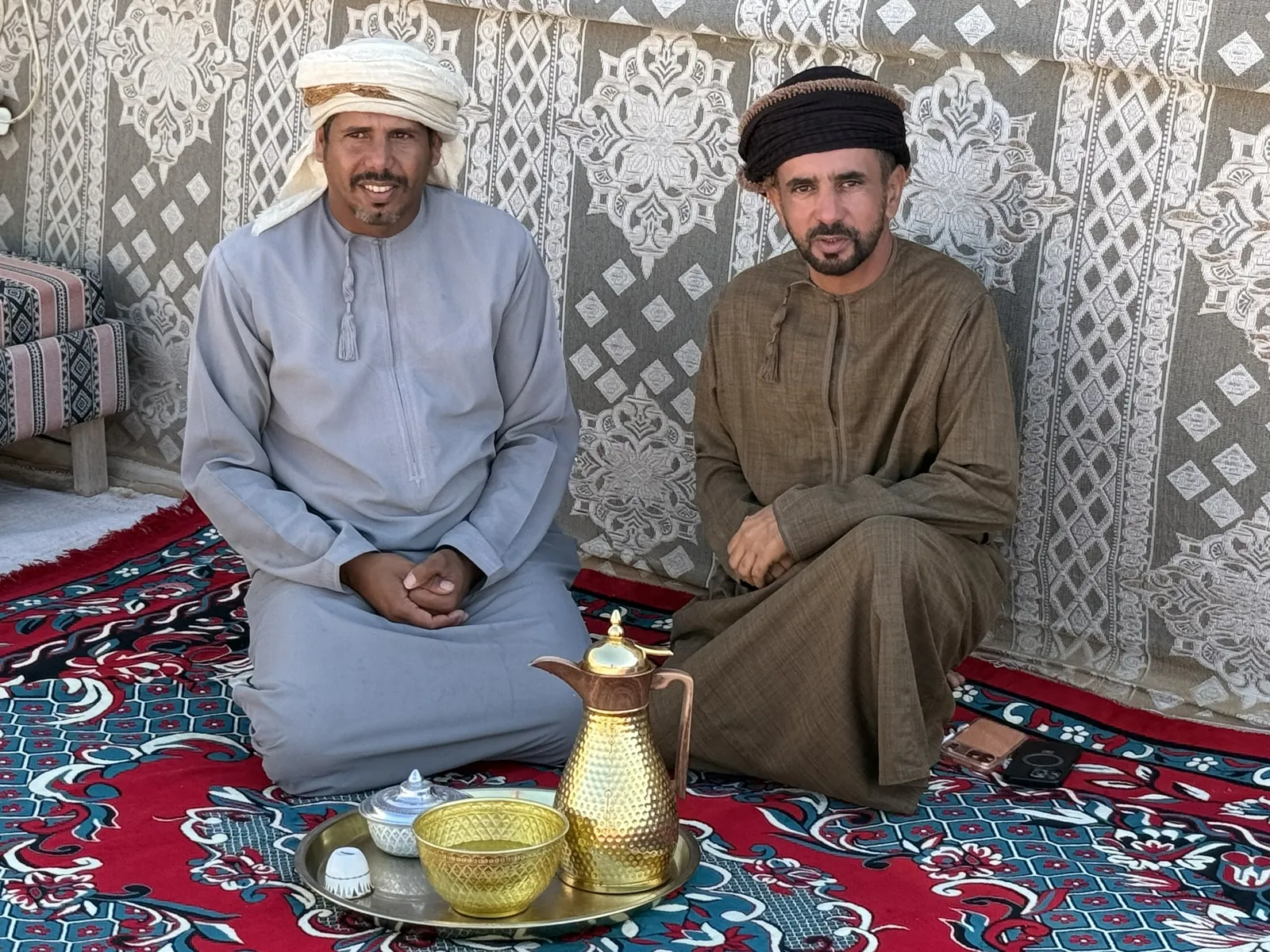 Omani hosts seated with a coffee pot and cups