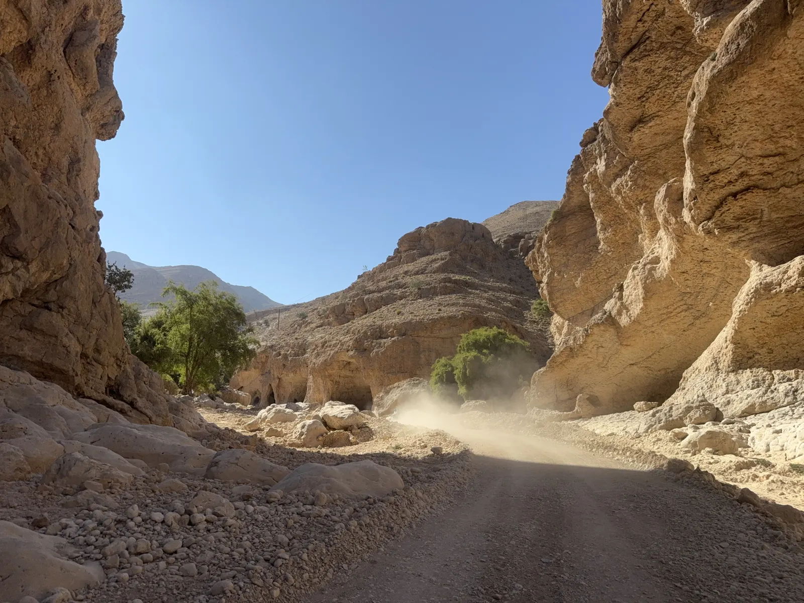 A UTV driving between rocky canyon walls on the route toward Wadi Bani Khalid