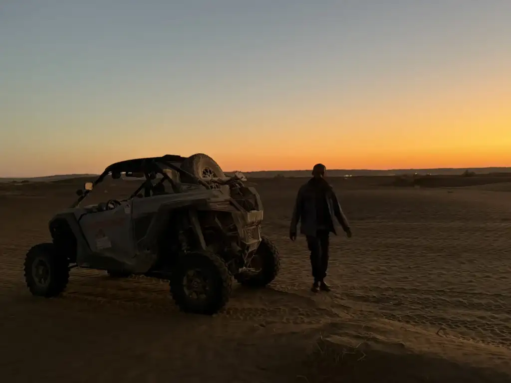 A participant and UTV on the sand at dusk in the Wahiba Sands area