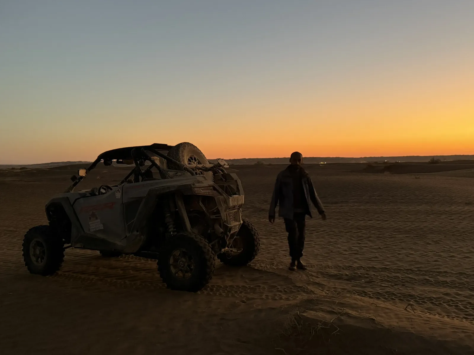 A participant and UTV on the sand at dusk in the Wahiba Sands area