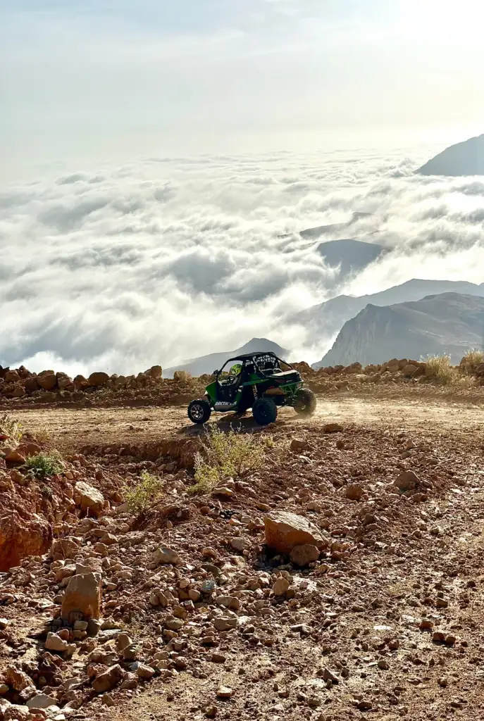 A FOX ATVS buggy on a mountain track above a layer of cloud