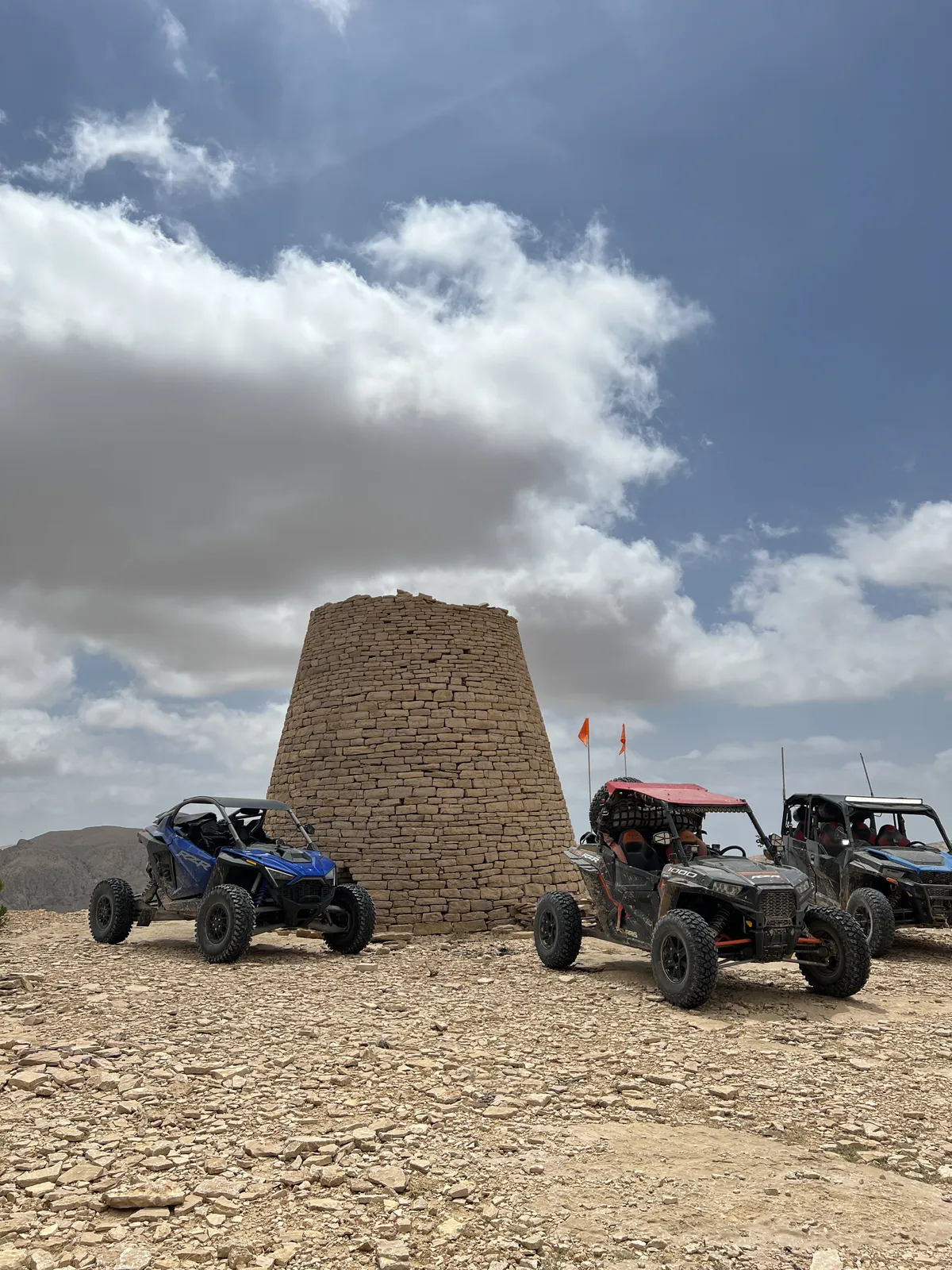 UTVs stopped beside a traditional stone tomb on a mountain route