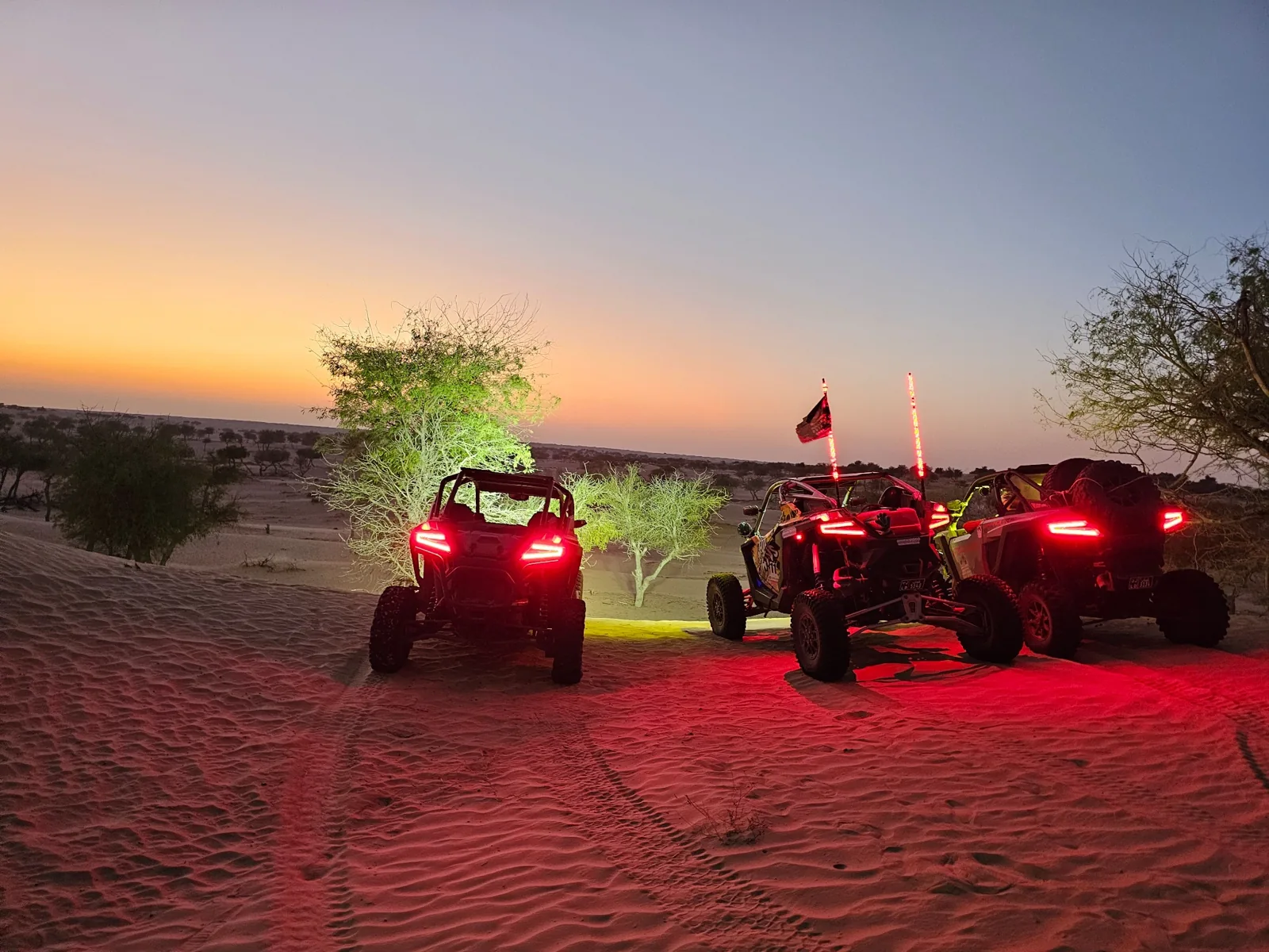 FOX ATVs vehicles with rear lights glowing at a desert stop at dusk
