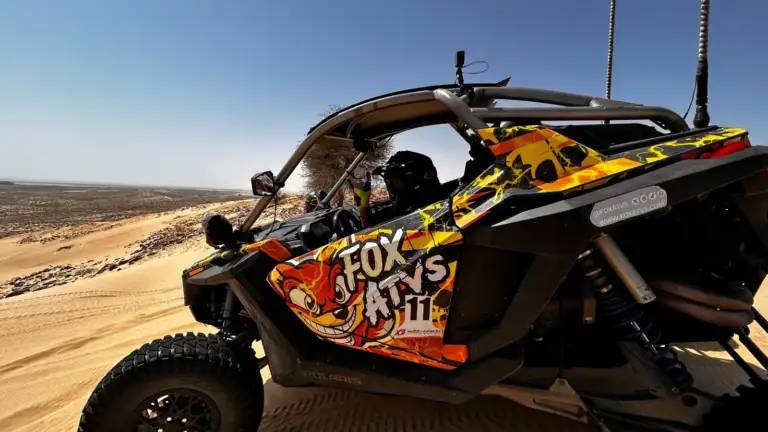 Helmeted driver in a FOX ATVs side-by-side on the dunes