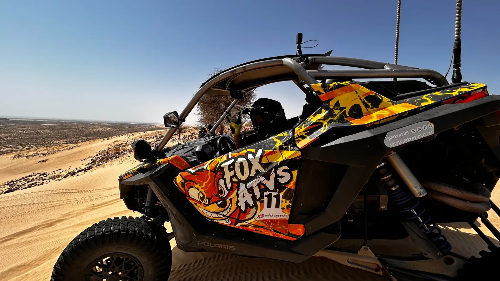 Helmeted driver in a FOX ATVs side-by-side on the dunes