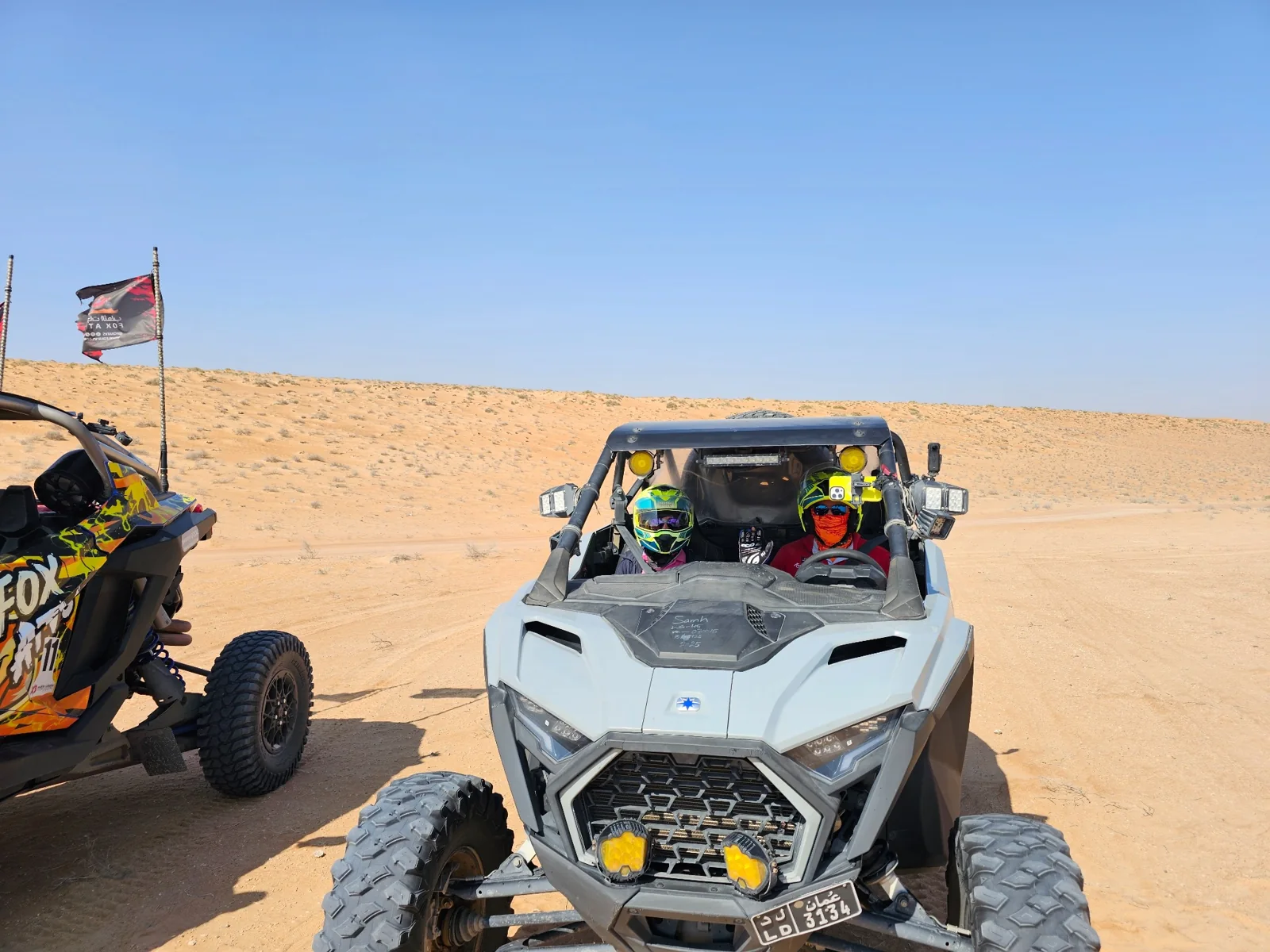 Guests wearing helmets in a two-seat FOX ATVs UTV at a desert stop
