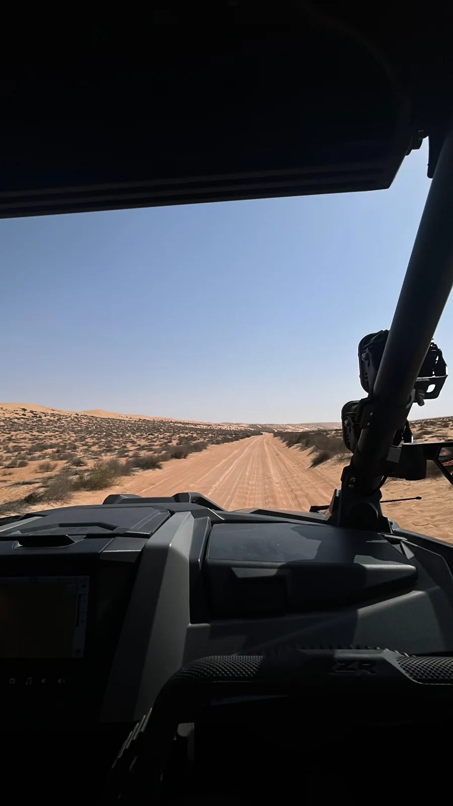 View of a sandy track and desert horizon from inside a FOX ATVs UTV