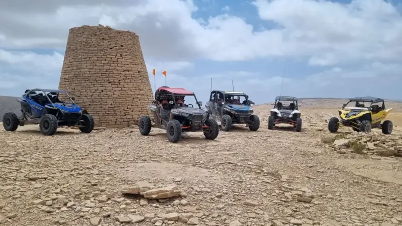 A FOXATVs convoy stopped beside a traditional stone tower in Oman