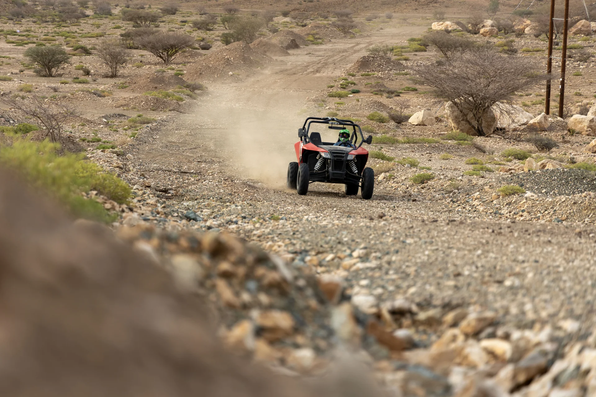 A side-by-side vehicle driving along a rocky wadi track