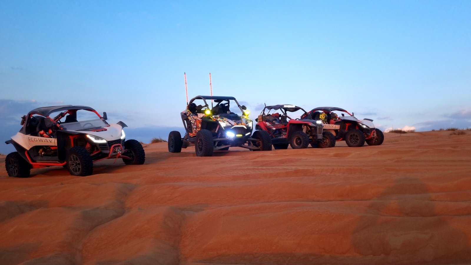 FOX ATVs expedition vehicles stand on orange Wahiba dunes in the evening light