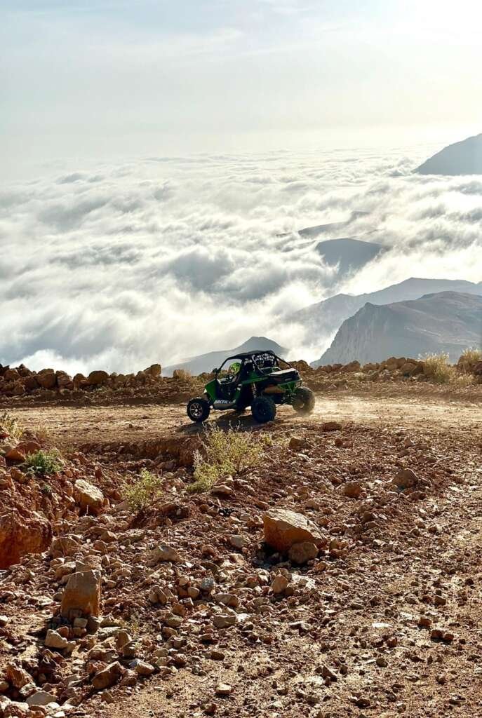 A FOX ATVs buggy follows a rocky mountain track above a sea of clouds
