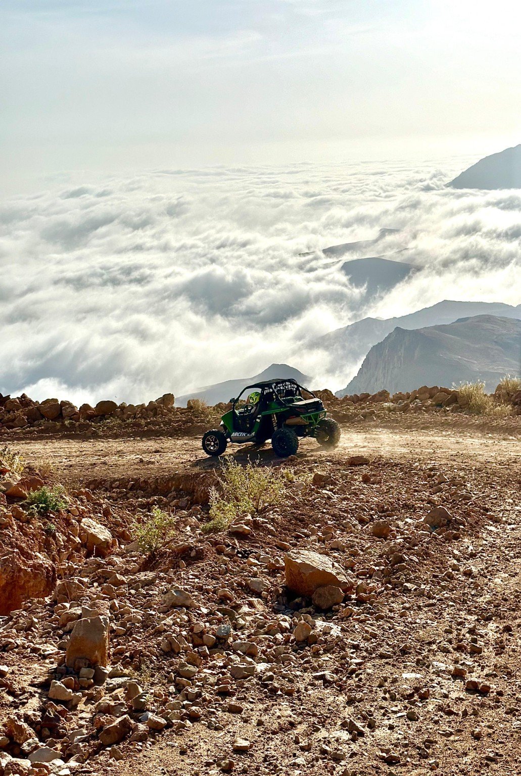 A FOX ATVs buggy follows a rocky mountain track above a sea of clouds