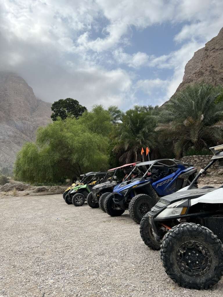 FOX ATVs expedition buggies beside palms and dramatic wadi cliffs in Oman